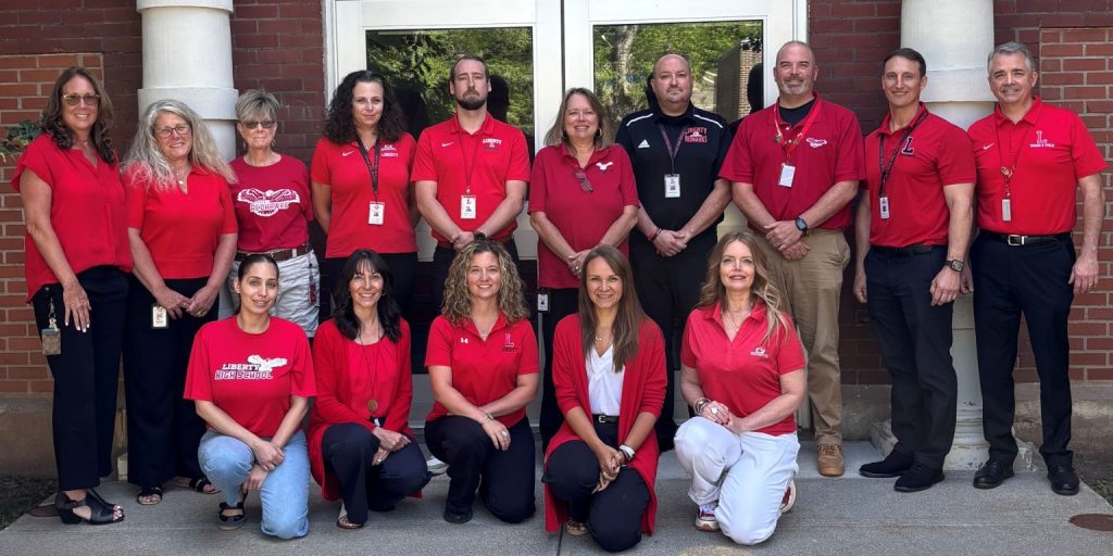 Members of the Liberty Central School District administration team wearing matching red shirts posing together outdoors.