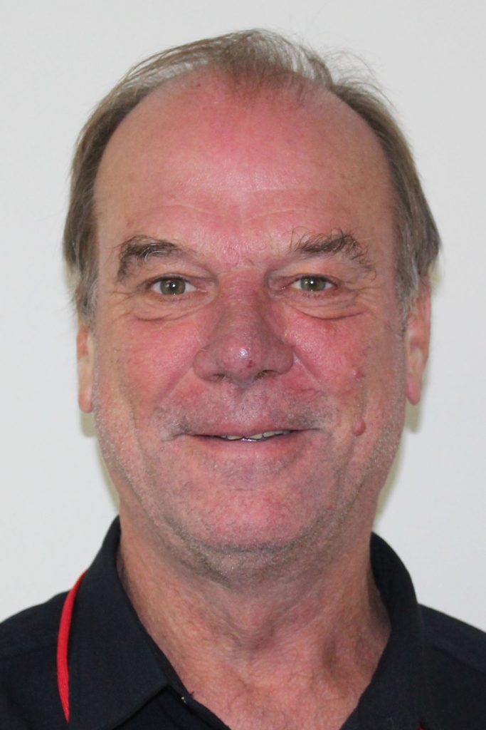 Headshot of patrick killian, a smiling man with short brown hair wearing a black polo shirt with red trim.