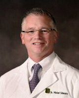 michael schwartz, alumni of liberty and honoree of wall of fame, portrait, wearing doctor jacket, smiling, wearing glasses, facing camera